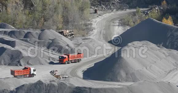 自卸卡车在花岗岩采石场行驶在采石场用重型机械开采石块视频的预览图