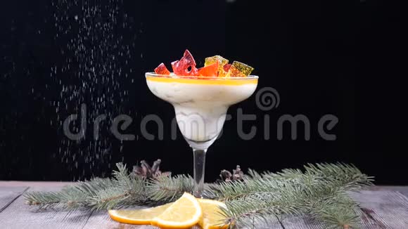 装饰着杉树枝和柠檬片的木板上的玻璃碗里的美味甜点孤立于黑色视频的预览图