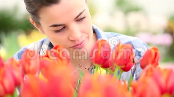 春天花园里带着郁金香微笑的女人视频的预览图