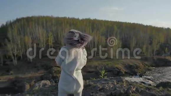 小女孩正在森林里的岩石上旋转慢动作视频的预览图