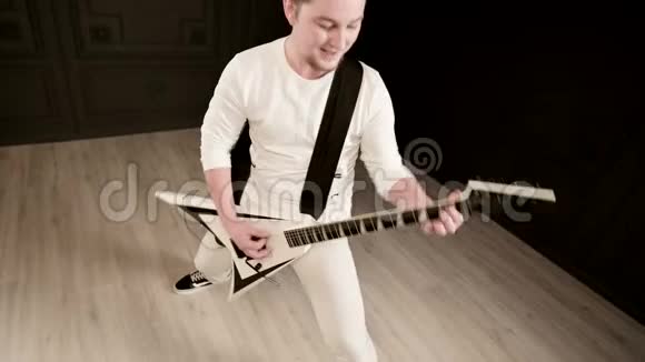 时尚的独奏吉他手头上戴着可怕的石头黑色背景上穿着白色衣服富有表现力地演奏着视频的预览图