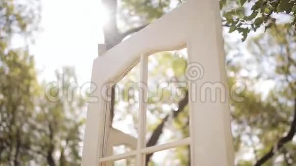 白色的拱门和带垫子的椅子婚礼拱门以乡村风格的门的形式太阳透过阳光照耀视频的预览图