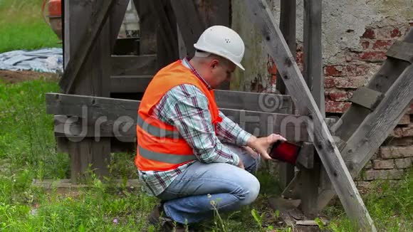 建筑工人检查木脚手架并在平板电脑上拍照视频的预览图