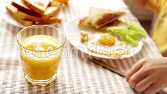男孩吃早餐包括煎蛋烤面包和橙汁视频的预览图