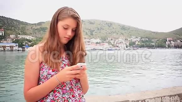 女孩在海上背景下使用智能手机视频的预览图