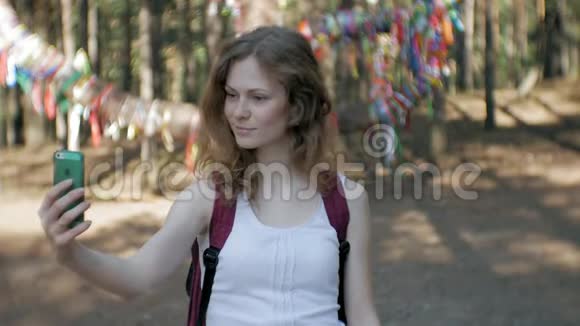 在森林里用智能手机的年轻女人漂亮的女孩在树林里打电话视频的预览图