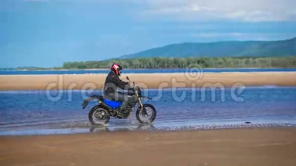 极端骑摩托车的人骑在河边的沙滩上视频的预览图