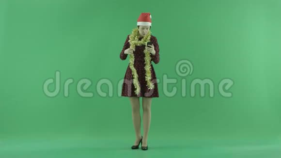 一位年轻的圣诞女士正在绿色屏幕上打电话视频的预览图