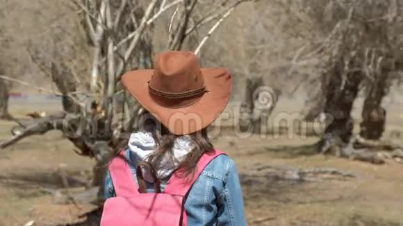 一个戴着宽边帽子的女孩欣赏森林环顾四周特写视频的预览图