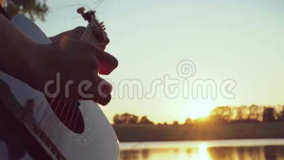 靠近傍晚池塘边弹吉他的女孩的手4k视频的预览图