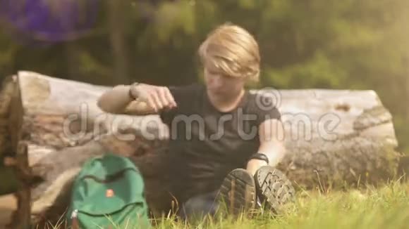 一个年轻的步行者来到一棵倒下的树干坐在阳光下休息视频的预览图