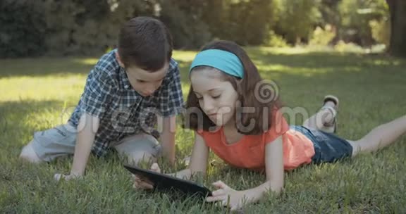 孩子们在户外草地上使用平板电脑视频的预览图