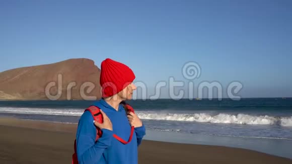 活跃的徒步旅行者女人在海滩上散步西班牙加那利群岛特内里费带背包的高加索年轻妇女视频的预览图