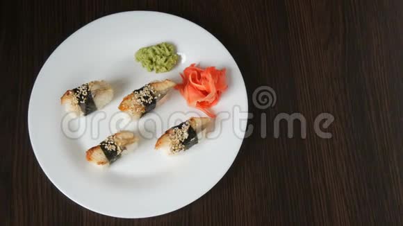 一个白色的大盘子上面放着四个巨大的寿司鳗鱼在粉红色的生姜和绿色的旁边倒着一块诺丽视频的预览图
