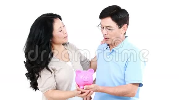 成熟的亚洲夫妇手里拿着储蓄罐视频的预览图