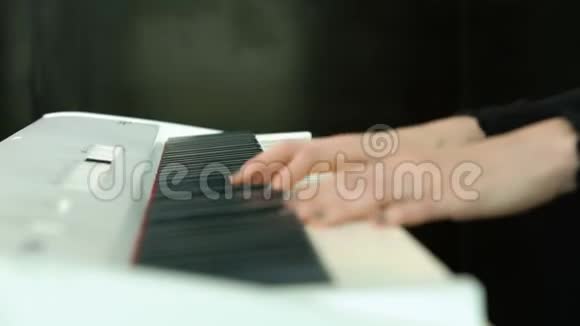 女子双手弹奏白色数字钢琴特写镜头配合离焦女孩用手指在键盘或视频的预览图