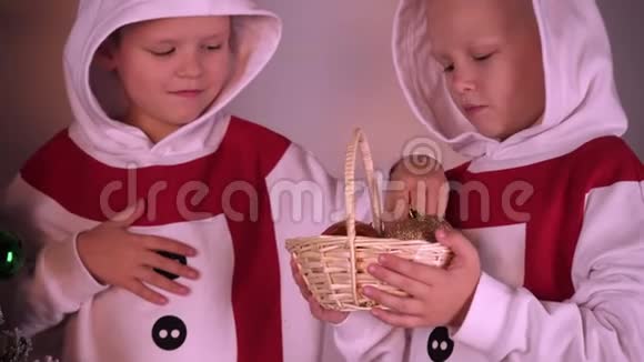 可爱的男孩穿着圣诞老人和雪人的节日服装用球和花环装饰圣诞树视频的预览图