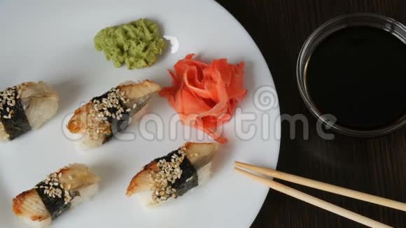 一个白色的大盘子上面放着四个巨大的寿司鳗鱼在粉红色的生姜和绿色的旁边倒着一块诺丽视频的预览图