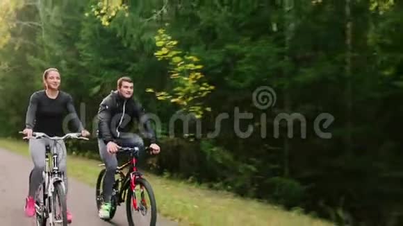 年轻夫妇在夏天的公园里骑自行车视频的预览图
