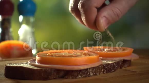 男人正在三明治上添加一些香料特写慢动作视频视频的预览图