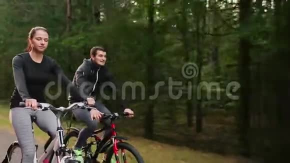 年轻夫妇在夏天的公园里骑自行车视频的预览图