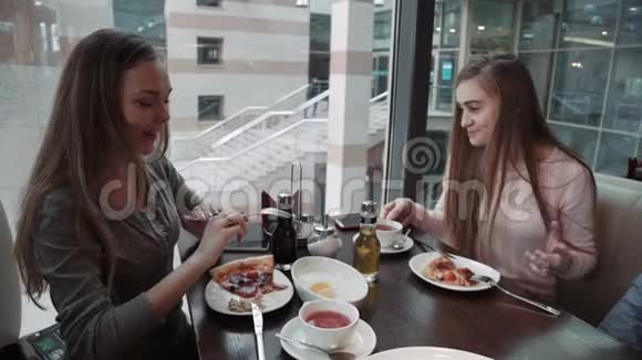 朋友两个年轻的女人在咖啡馆见面商务午餐聊天吃意大利披萨视频的预览图