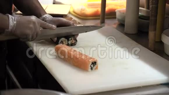 用刀切橘子寿司卷的过程男人用竹垫卷起寿司准备好的寿司卷视频的预览图