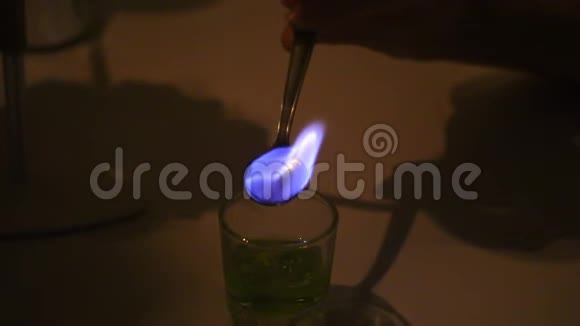 一个人准备一杯苦艾酒糖用烈性饮料滋润在茶匙中燃烧视频的预览图