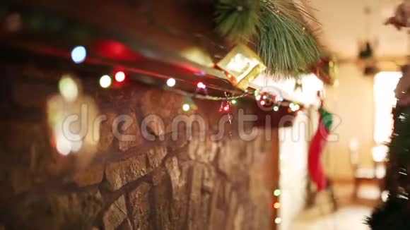 穿着针织毛衣的人把圣诞花环挂在石头上用五颜六色的闪光花环装饰着真正的壁炉视频的预览图