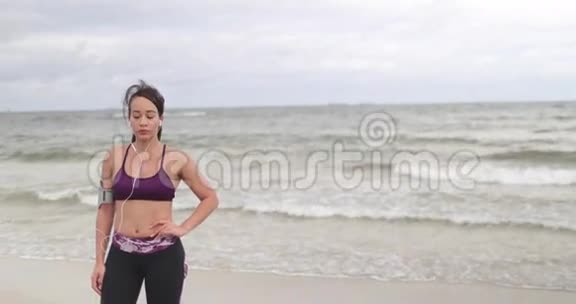 少妇在阴天在海滩上慢跑后休息健身慢动作视频的预览图