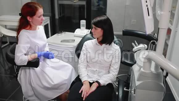 美丽的女孩在他办公室的一个牙科医生的球上疼痛指向她的牙齿白色无菌视频的预览图