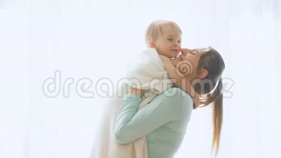 快乐的年轻母亲在窗口搂着她的小儿子的慢镜头视频的预览图