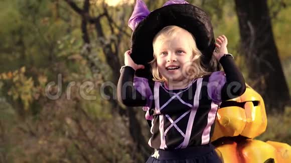 穿着女巫服装和南瓜杰克在一起的小女孩穿着万圣节女巫服装的滑稽女孩视频的预览图