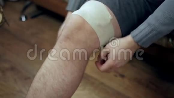 年轻人用弹力绷带包扎膝盖受伤的伤口视频的预览图