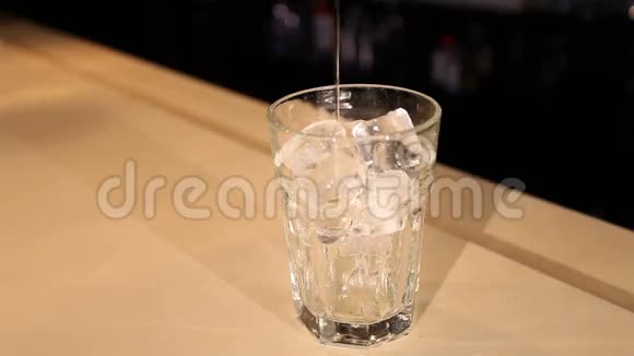酒保把酒倒入装有冰块的玻璃中视频的预览图