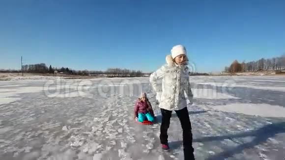 女孩在冰冻的湖面上雪橇姐姐视频的预览图