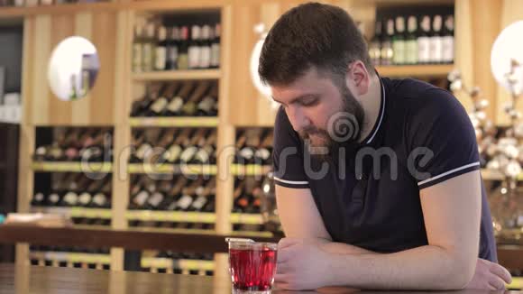 在餐馆或咖啡馆喝红饮料的男人在喝红鸡尾酒时使用智能手机的年轻人视频的预览图