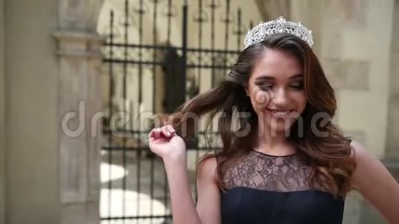 迷人的女孩黑发穿着深蓝色长裙带花边皇冠摆姿势视频的预览图