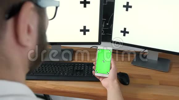 男人拿着平板电脑和手表电视绿色屏幕男人手里拿着手机绿屏看电视视频的预览图