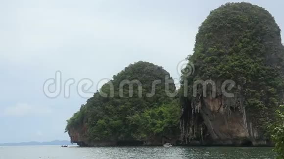 靠近海滩和游艇的蔚蓝海中有岩石的岛屿视频的预览图