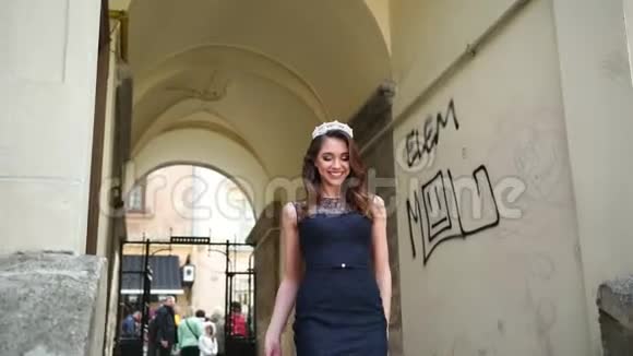 美丽的女孩黑发穿着深蓝色长裙带花边皇冠摆姿势视频的预览图