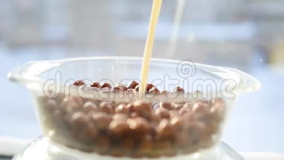 喷射牛奶慢慢地掉进一个带有巧克力味的玉米球的碗里慢动作视频的预览图