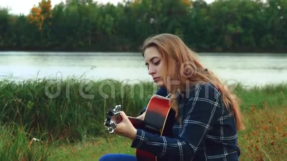 女性手弹吉他一个快乐无忧无虑的小女孩独自在树林里弹吉他当她在森林里的时候视频的预览图