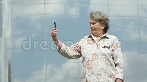 老年妇女使用银色智能手机拍照视频的预览图