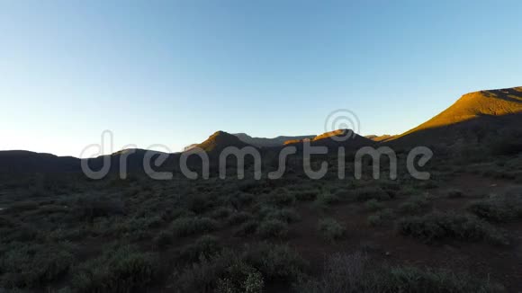 南非卡鲁国家公园纳米布沙漠上五彩缤纷的日落晴朗的天空发光的岩石和山丘时间流逝的视频视频的预览图