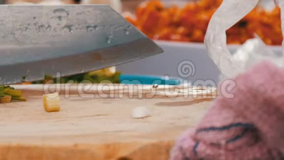 女人用一把大刀在厨房的木板上切绿色蔬菜和炊具旁边泰国街头食品视频的预览图