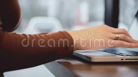 女人的手在咖啡座的笔记本电脑里工作视频的预览图
