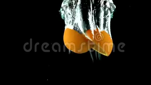 特写橙色分裂成两半并沉入水中的超慢动作视频视频的预览图