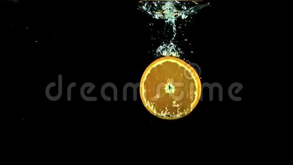 橙色片在黑色背景下落入水中的超级慢动作视频视频的预览图