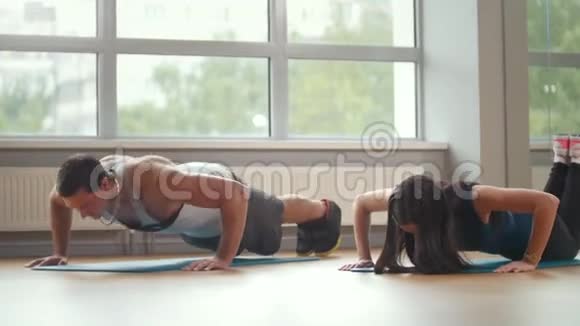 健身女孩和男人一起在健身房做俯卧撑视频的预览图